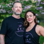 MET_FeaturedImage - Carroll News | Carroll Publications | Carroll County, MD Two adults in black The MET shirts posing outdoors under flowering pink blossoms, smiling at the camera.