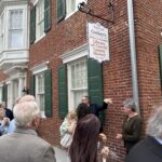 1778279171027-image-1 - Carroll News | Carroll Publications | Carroll County, MD Crowd of people gathered outside a brick building with a hanging sign reading 'Cockey's Library of Carroll County History' outside the Historical Society.