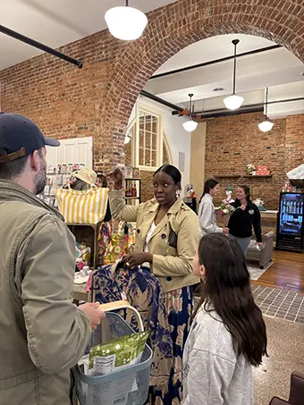 flower-jazz-fest - Carroll News | Carroll Publications | Carroll County, MD Woman in beige jacket speaks with a man pushing a shopping basket inside a brick-walled store.