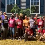 habitat-carroll-county - Carroll News | Carroll Publications | Carroll County, MD Group of volunteers posing outside a gray building, many waving at the camera. (Informative group photo)