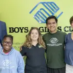 B&GC-Group Photo - Carroll News | Carroll Publications | Carroll County, MD Group of five smiling people standing together in front of a Boys & Girls Clubs sign and logo (two adults on ends, three youths in the center).