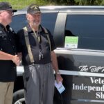 1788470983872-IMG_2824 - Carroll News | Carroll Publications | Carroll County, MD Two veterans shake hands beside a dark van with 'Veterans Independence Shuttle' lettering visible on the side.