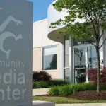 FeaturedImage_CMC - Carroll News | Carroll Publications | Carroll County, MD Front view of a community media center with a tall sign reading 'community media center' and a landscaped entrance with glass doors and trees.