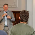 Johnny O Constitution Day_FeaturedImage - Carroll News | Carroll Publications | Carroll County, MD Man in a gray suit speaks into a microphone to a small audience in a conference room