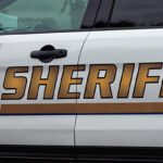 Side,View,Of,Sheriff's,Car,Door,With,Sheriff,Text,Symbol. - Carroll News | Carroll Publications | Carroll County, MD Side of a white sheriff patrol SUV with large gold SHERIFF lettering and blue stripe on the door surface of the vehicle, front and rear doors visible.