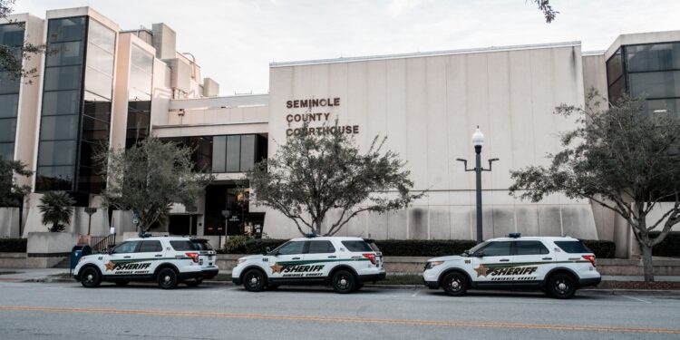 Front view of the Seminole County Courthouse with sheriff patrol cars parked along the curb in front of the building
