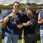 Jesse-Farace-Trey-Harkins-Tim-Koelber & Zachary Kropkowski - Carroll News | Carroll Publications | Carroll County, MD Group of four men standing under a white tent at an outdoor festival, holding drinks and snacks and posing for the camera.