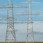 power-lines-carroll-county - Carroll News | Carroll Publications | Carroll County, MD Metal lattice transmission towers carrying high‑voltage lines across a flat field under a blue sky.